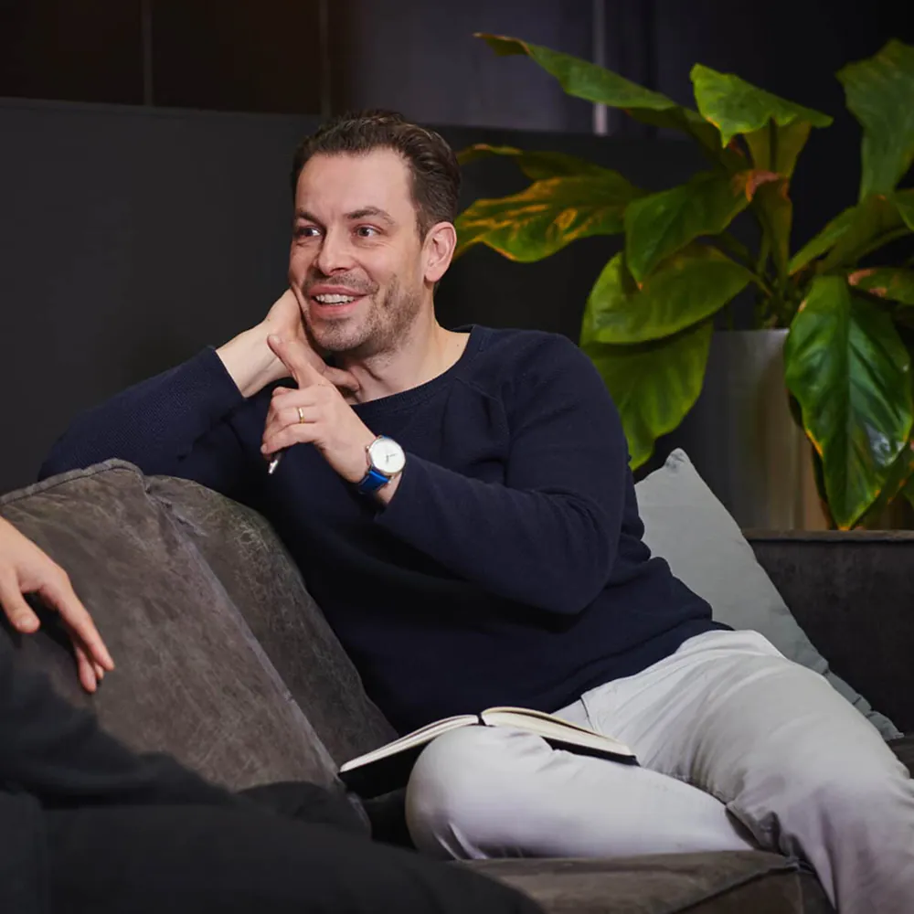 Man voert een één-op-één gesprek op een bank met een notitieboekje op schoot | Mr Cashflow